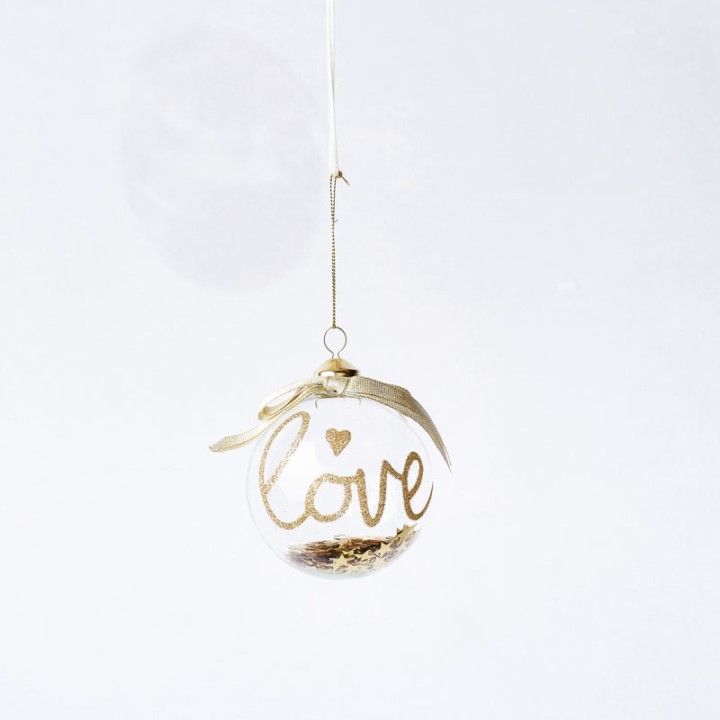 A clear glass ornament with a gold "love" script and a delicate ribbon.
