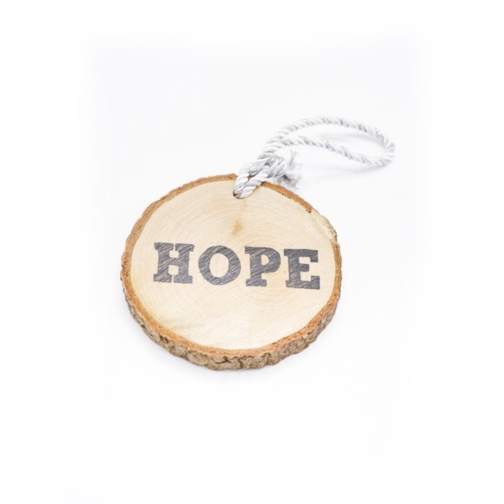 A wooden slice featuring the word "HOPE" carved on it, with a white rope for hanging.