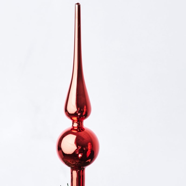 A shiny red glass ornament with a pointed top and a round middle, reflecting light beautifully.