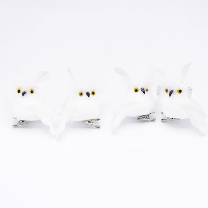 Vier schattige, witte uiltjes met gele ogen, bevestigd op metalen clips.