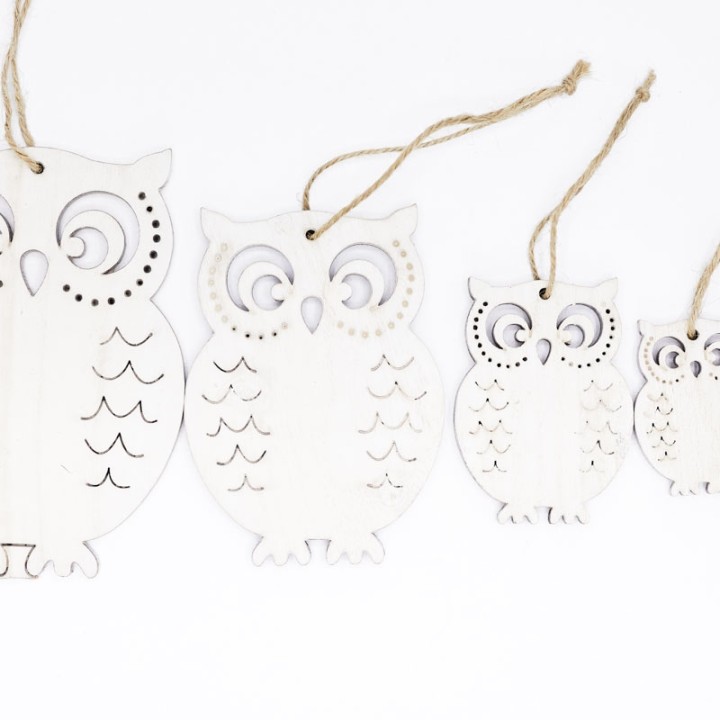 Quatre hiboux en bois blanc, décorés de motifs découpés, suspendus par une corde.