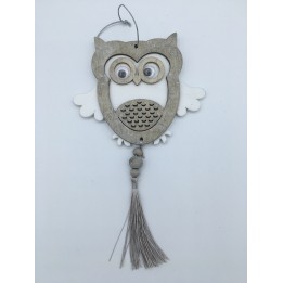 A wooden owl ornament with large eyes, white wings, and a decorative tassel below.