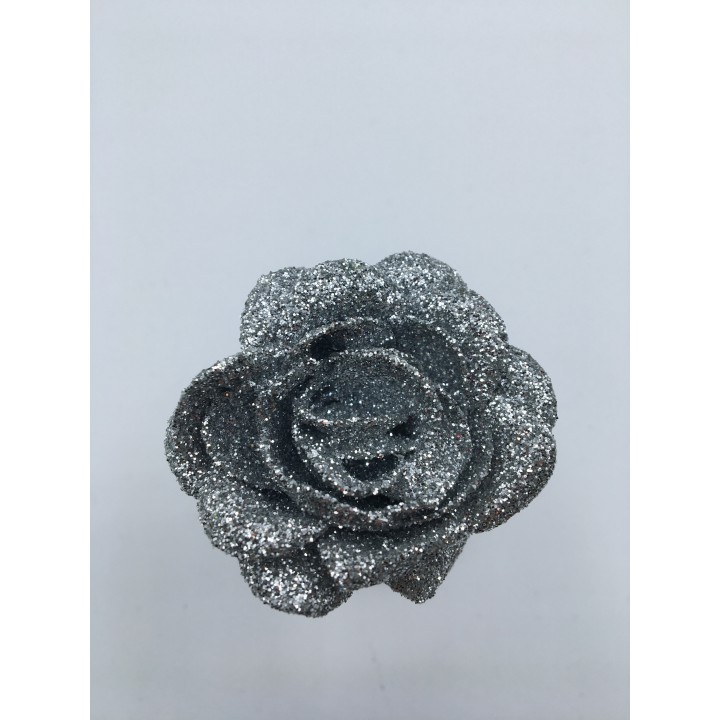 Glanzende, zilveren rozenknop bedekt met glitters op een lichte achtergrond.