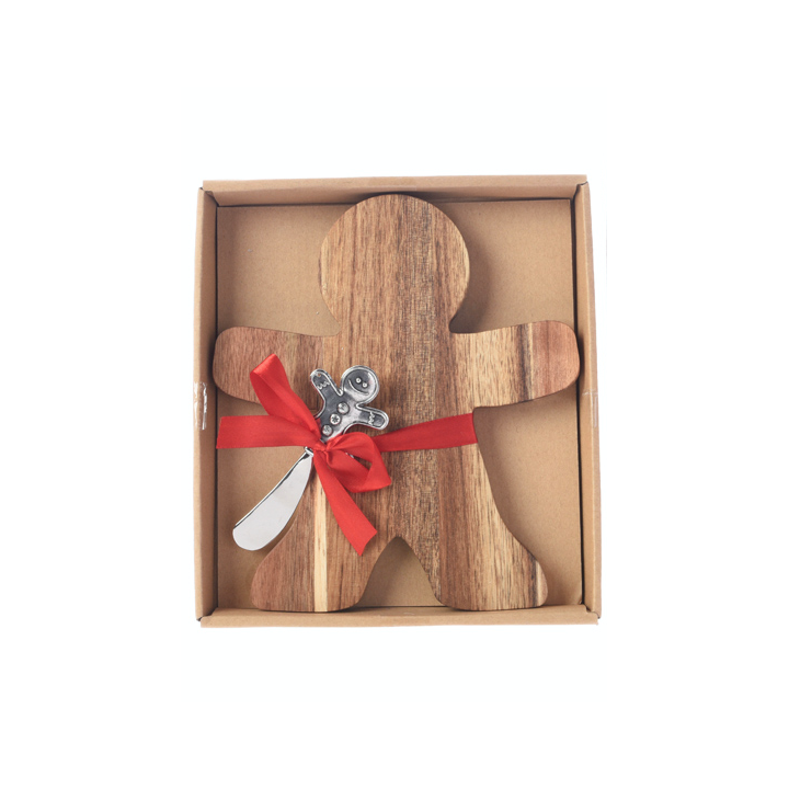 A wooden gingerbread man with a silver spoon, tied with a red ribbon in a box.