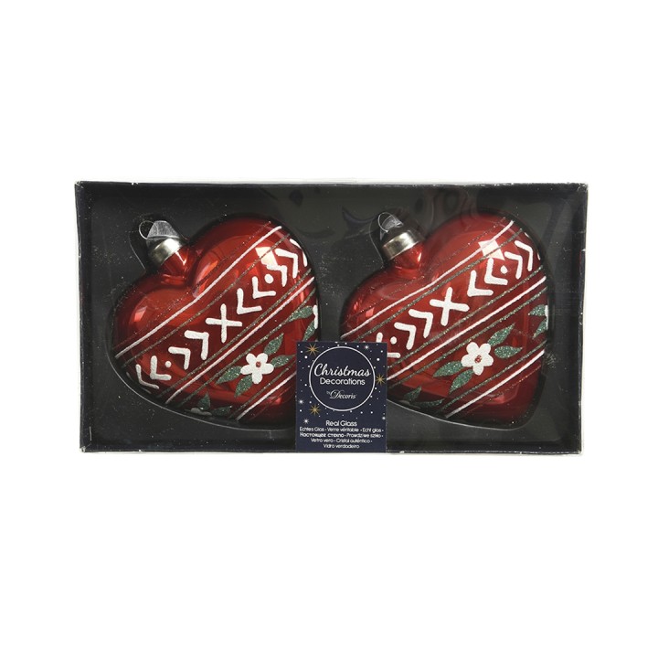 Two red heart-shaped Christmas ornaments with white patterns and floral accents in a box.