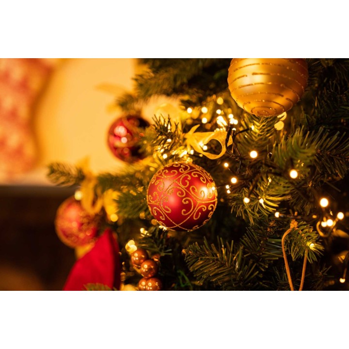 A festive Christmas tree adorned with red and gold ornaments, twinkling lights, and greenery.
