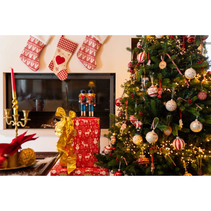 A cozy holiday scene with a decorated tree, gifts, and stockings above a fireplace.