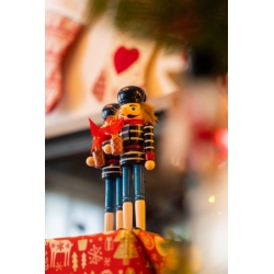Kleurrijke houten notenkrakers met een feestelijke uitstraling, versierd met bladeren en cadeau.