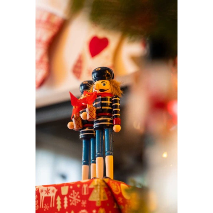 Two colorful nutcracker figures, one holding a basket, set against festive decorations.