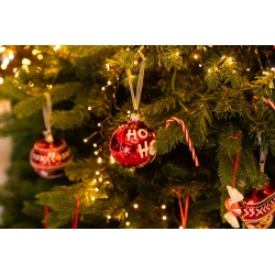 Boules de Noël rouges et dorées suspendues à un sapin lumineux, décorations festives.