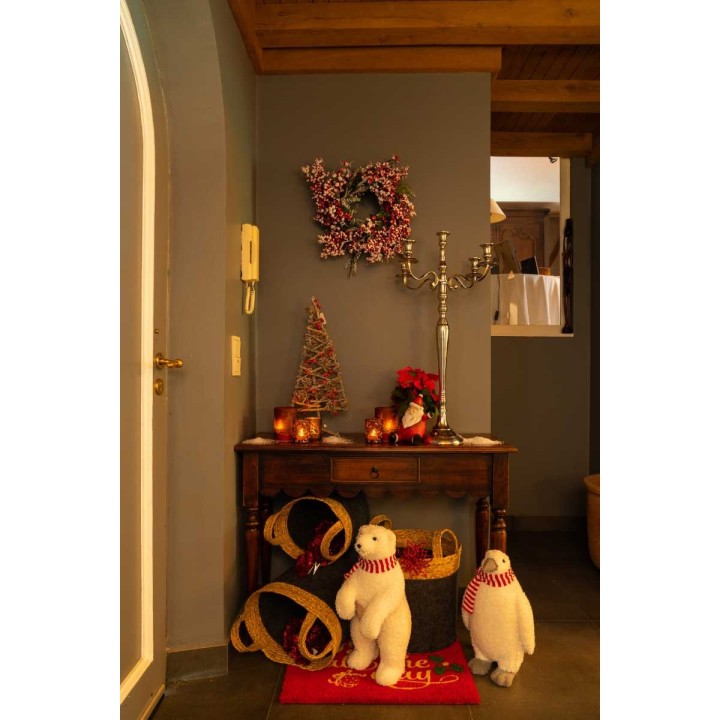 A cozy entryway with festive decor, featuring plush snowmen, candles, and a small tree.