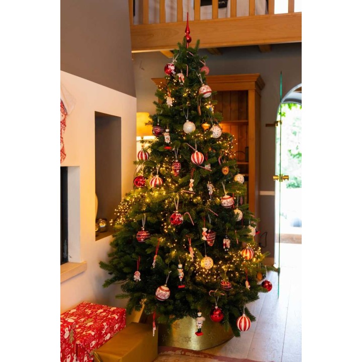 Un sapin de Noël décoré de boules rouges et blanches, illuminé et entouré de cadeaux.