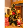 Kerstboom met gouden versieringen, rode strik, cadeaus en een kerstman in een warme woonkamer. Kerstboom met gouden versieringen, rode strik, cadeaus en een kerstman in een warme woonkamer.