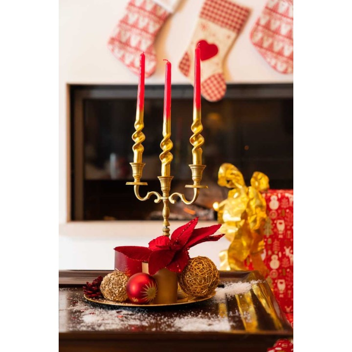 A golden candle holder with red candles, surrounded by festive decorations and gifts.