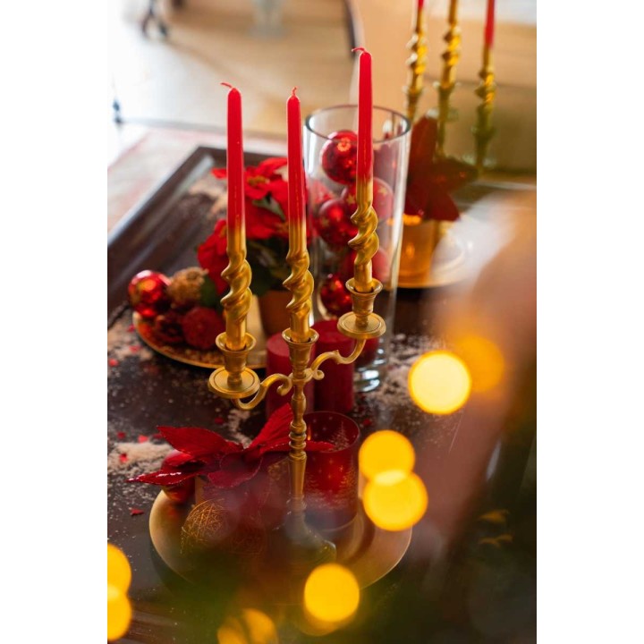 Elegant golden candlesticks hold red candles, surrounded by festive decor and soft lights.
