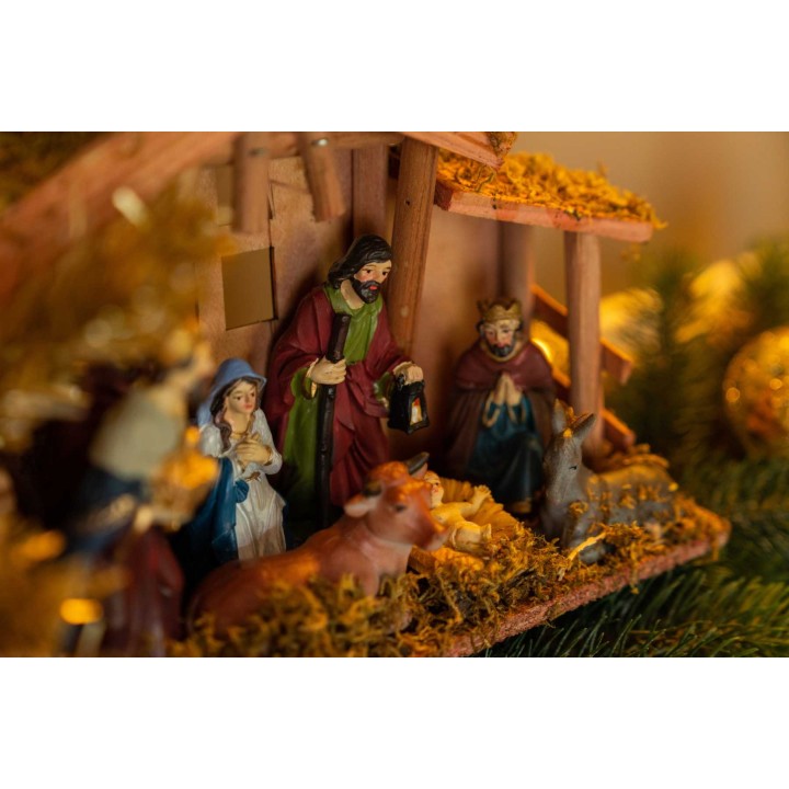 Scène de crèche avec figurines colorées, paille dorée et ambiance chaleureuse de Noël.