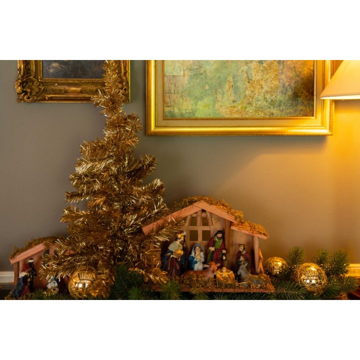 Scène de Noël chaleureuse avec crèche, sapin doré et décorations scintillantes.