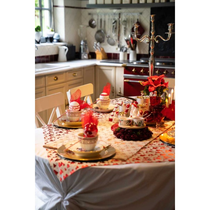 Elegante eettafel met rood-witte serviezen, gouden schalen en een sfeervolle kaarsenhouder.