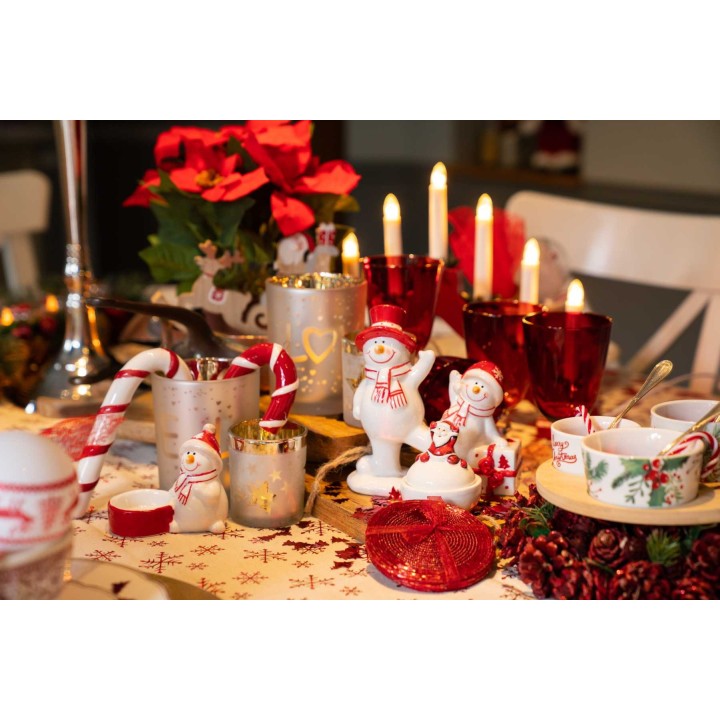 Feestelijke tafelsetting met kerstdecoraties, sneeuwpoppen, kaarsen en rode accenten.