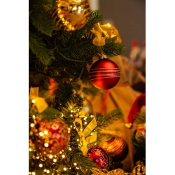 A close-up of a festive Christmas tree adorned with shiny red and gold ornaments.