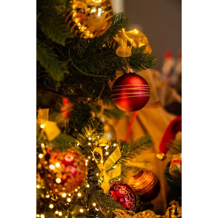 Ornements dorés et rouges, guirlandes lumineuses, sapin festif décoré avec soin.