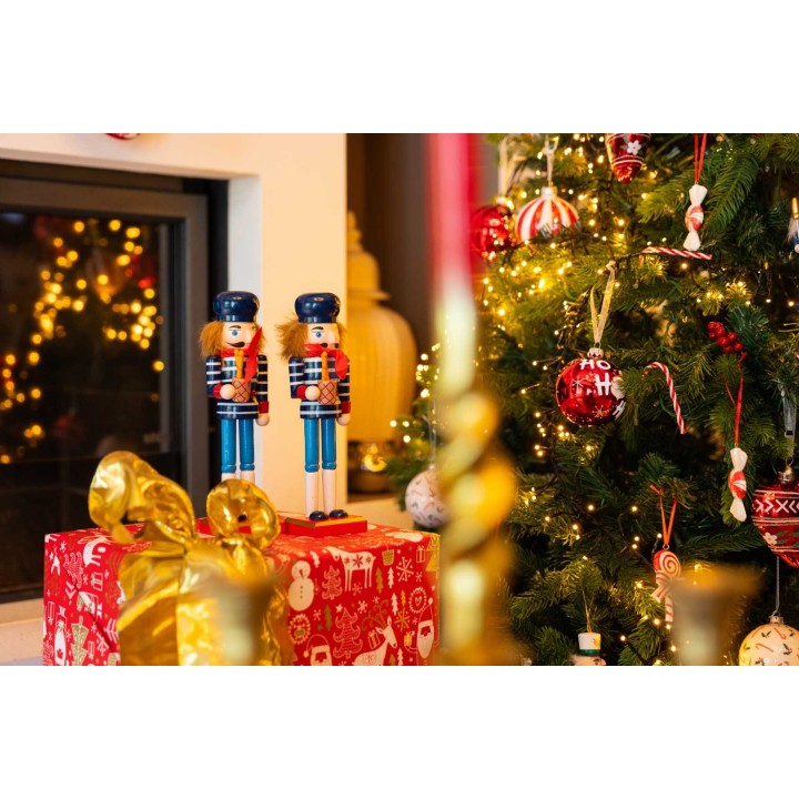 Kerstdecoraties met notenkrakers, een dennenboom en feestelijke lichten, warme kleuren.