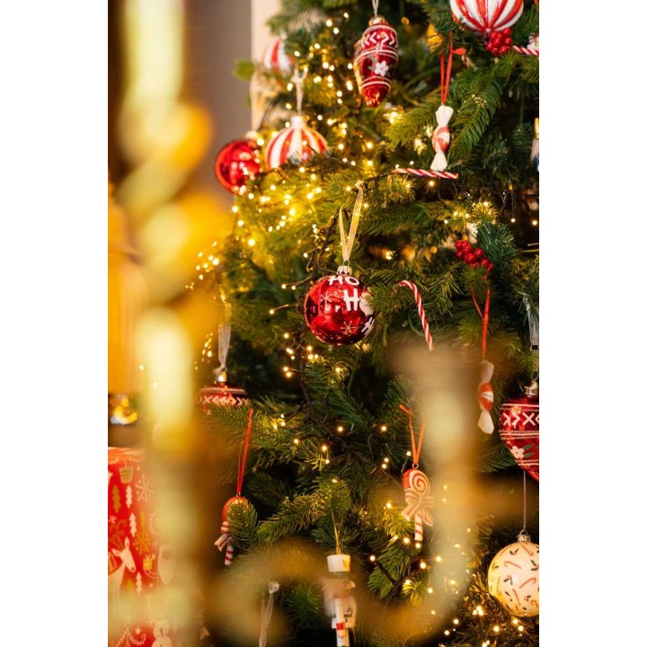 A festive Christmas tree adorned with red and white ornaments, candy canes, and twinkling lights.
