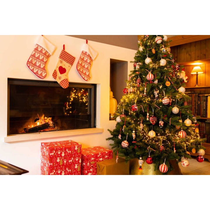 A cozy holiday scene with a decorated Christmas tree and stockings by a warm fireplace.