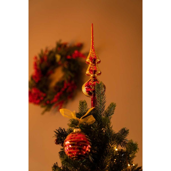 Sapin décoré avec une étoile dorée, boules rouges, et une couronne festive en arrière-plan.