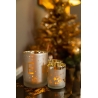 Drie glazen kaarsenhouders met gouden accent, omgeven door een feestelijke sfeer en decoraties.