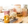 A festive table setting with a gold ornament, colorful candles, and scattered confetti.