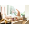 A cozy holiday table with candles, decorative gnome, and textured ornaments.
