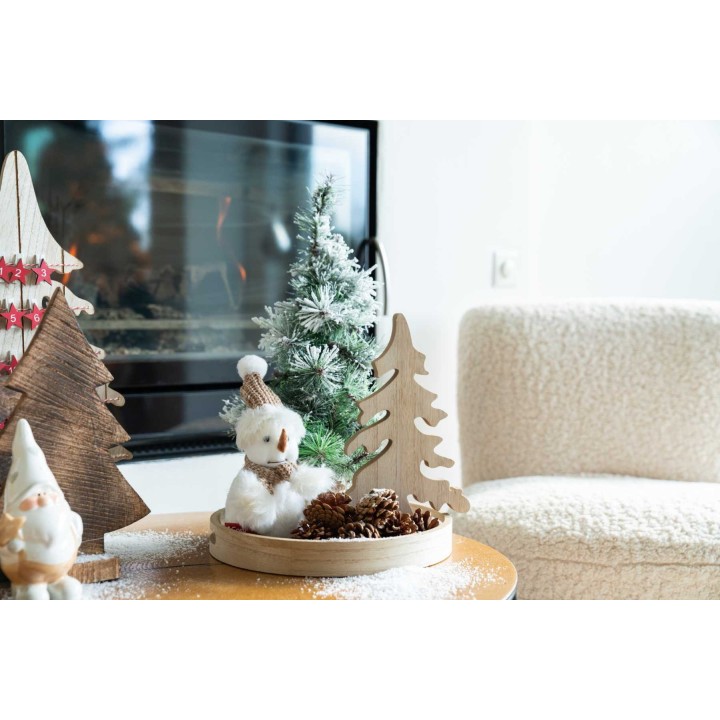 A cozy holiday scene with wooden trees, a snowy figure, and pinecones on a table.