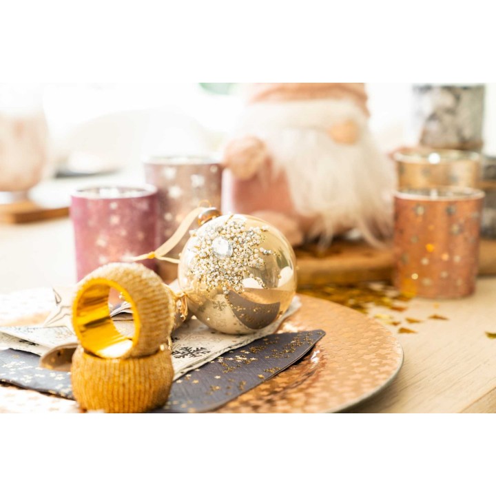 Décor festif avec une boule dorée, des bougies et des éléments scintillants sur une table él...