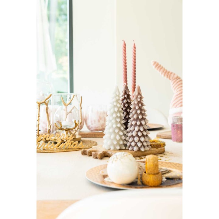 Décoration de fête : sapins en cire, bougies roses et douceurs sur une table élégante.