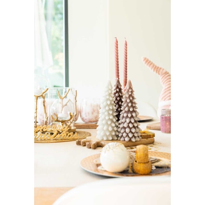 Sfeervolle tafel met pastelgekleurde kaarsen, kerstbomen en decoratieve schalen.