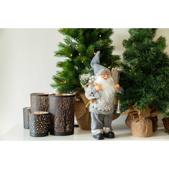 Kerstdecoraties met een kerstman, groene bomen en sfeervolle, lichtgevende kaarsenhouders.