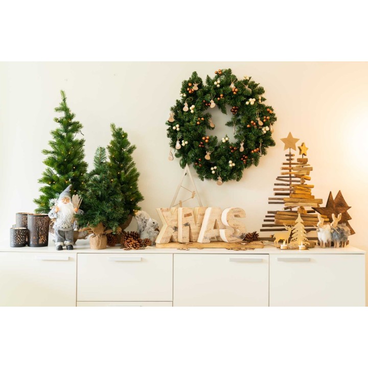 Een feestelijke kerstdecoratie met houten elementen, groene bomen en een krans.
