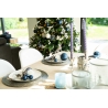 A festive dining table with elegant blue accents, surrounded by a decorated Christmas tree. A festive dining table with elegant blue accents, surrounded by a decorated Christmas tree.