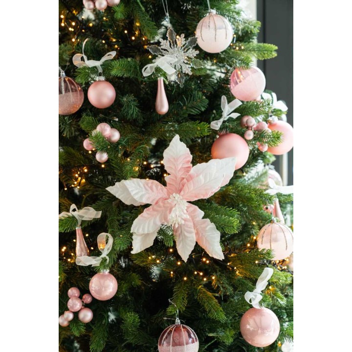 Een groene kerstboom versierd met roze ballen, een grote roze bloem en glinsterende sneeuwvlokken.