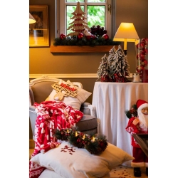 Ambiance chaleureuse de Noël avec décorations luxuriantes et couleurs festives.