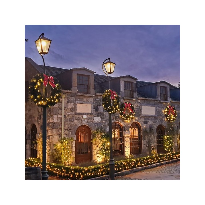 Bâtiment en pierre décoré de guirlandes lumineuses et de couronnes de Noël sous un ciel crép...