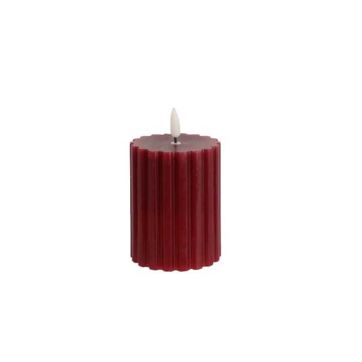 Bougie cylindrique rouge avec une finition plissée et une mèche blanche en haut.