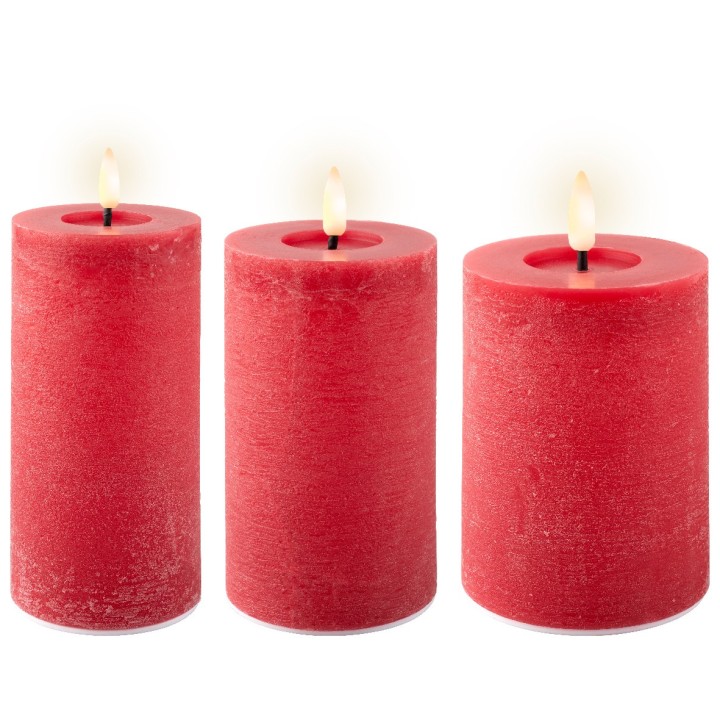 Three tall, textured red candles with gentle flames flickering on top.