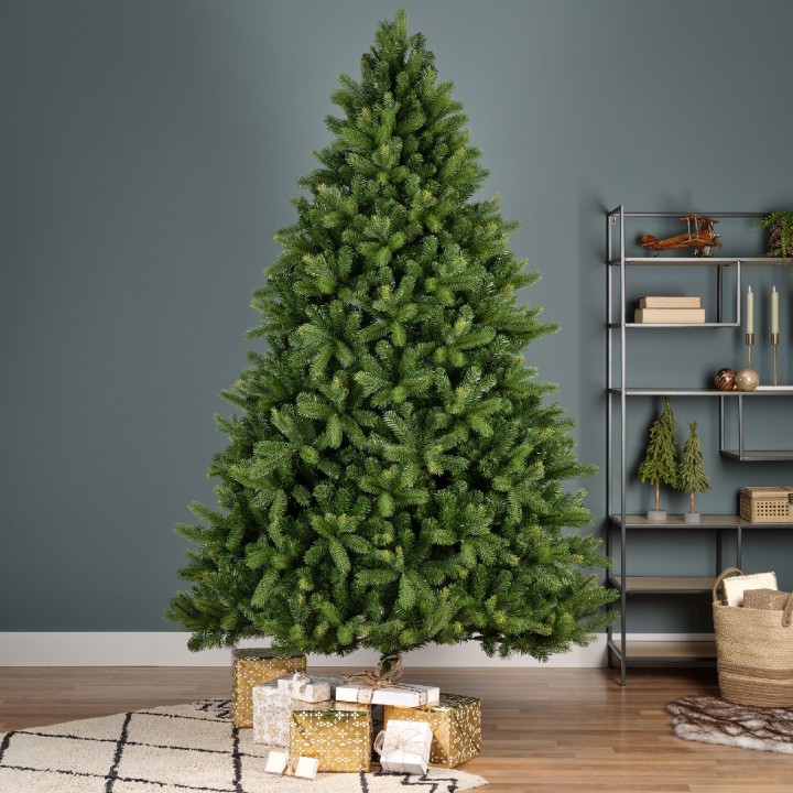A lush green Christmas tree stands in a cozy room with wrapped gifts beneath it.