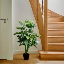A lush green plant in a black pot beside a wooden staircase with smooth, light-colored steps.