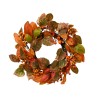Couronne automnale ornée de feuilles orange et dorées, baies rouges et touches vertes.