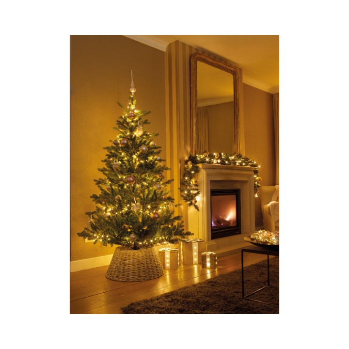 A warmly lit living room with a decorated Christmas tree and cozy fireplace.
