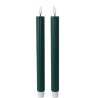 Two tall, dark green candles with white bases and flickering flames on top.