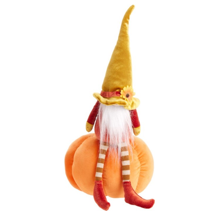 A whimsical gnome with a tall hat sits atop a soft, plush pumpkin.